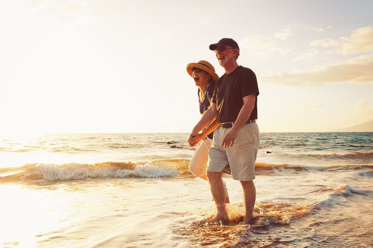 Older couple walking on the beach at sunset